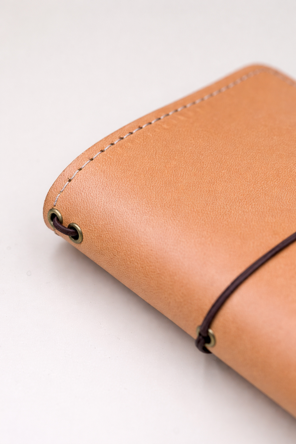 Passport size (B7) leather bi-fold journal cover in colour tan / beach sand spine side on view