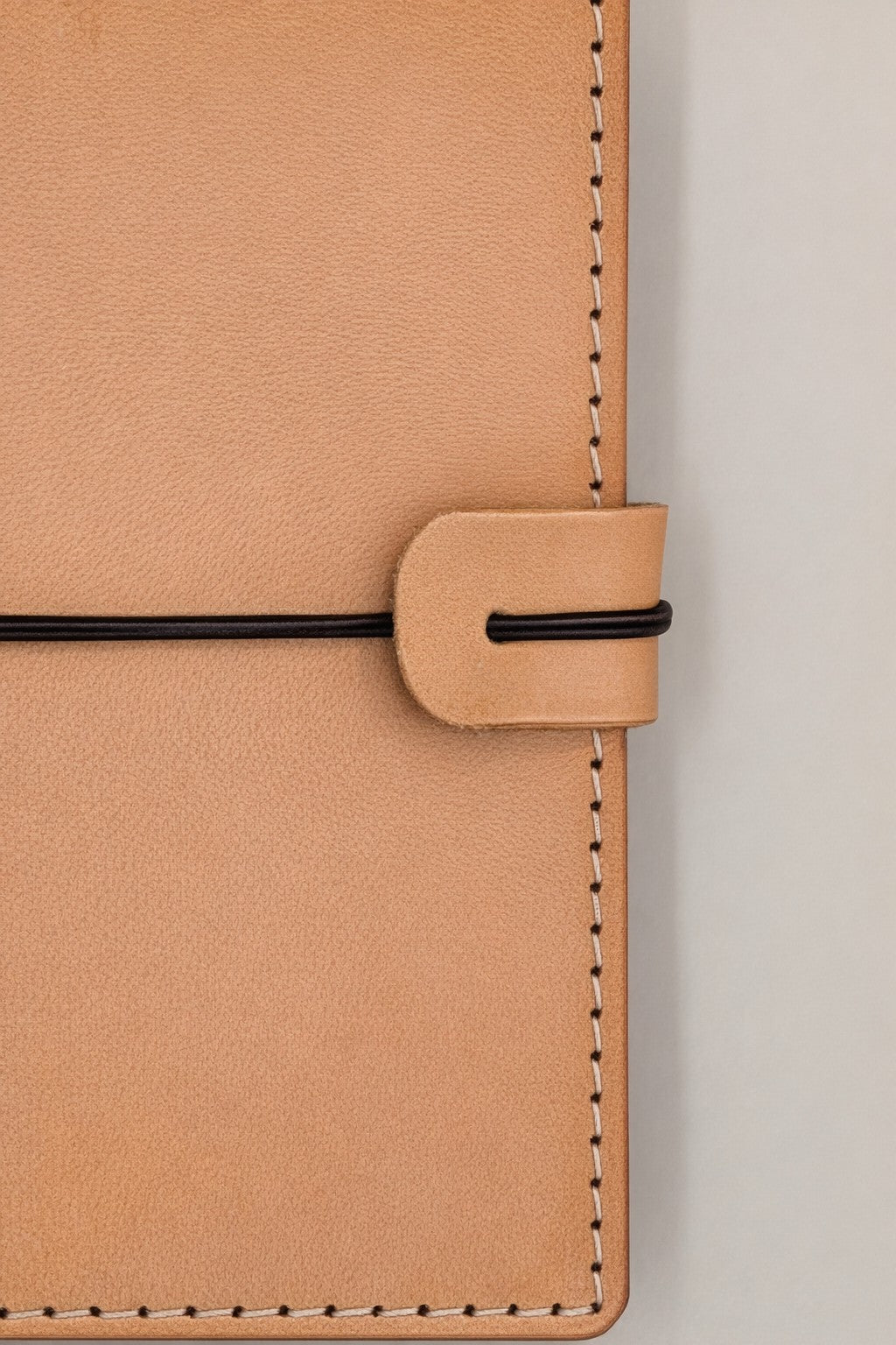 Passport size (B7) leather bi-fold journal cover in colour tan / beach sand detail view closure strap