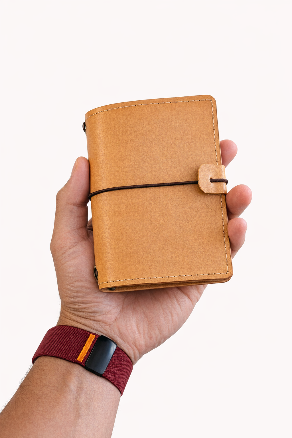 Passport size (B7) leather bi-fold journal cover in colour tan / beach sand held in hand